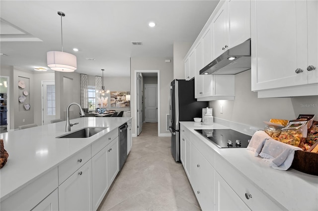 kitchen with black electric cooktop, hanging light fixtures, light tile flooring, white cabinets, and sink