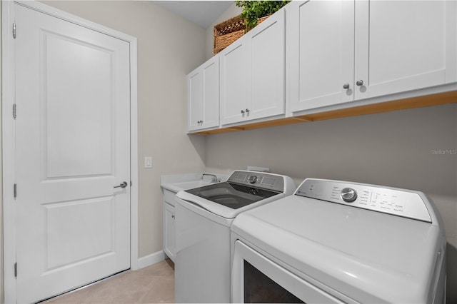 washroom with sink, light tile flooring, cabinets, and washing machine and clothes dryer