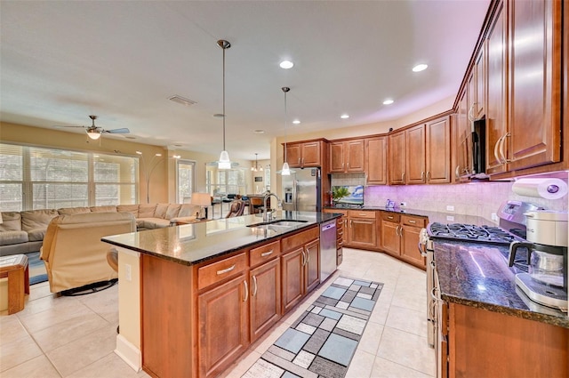 kitchen featuring stainless steel appliances, ceiling fan, a kitchen island with sink, sink, and hanging light fixtures