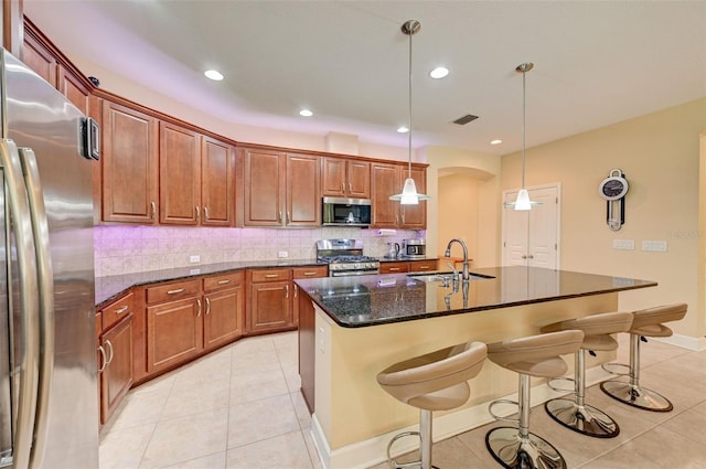 kitchen featuring sink, decorative light fixtures, a breakfast bar area, a kitchen island with sink, and appliances with stainless steel finishes