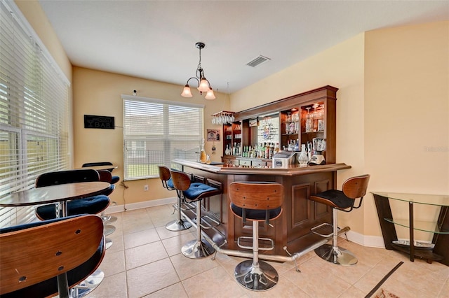 bar with pendant lighting, a notable chandelier, and light tile patterned flooring