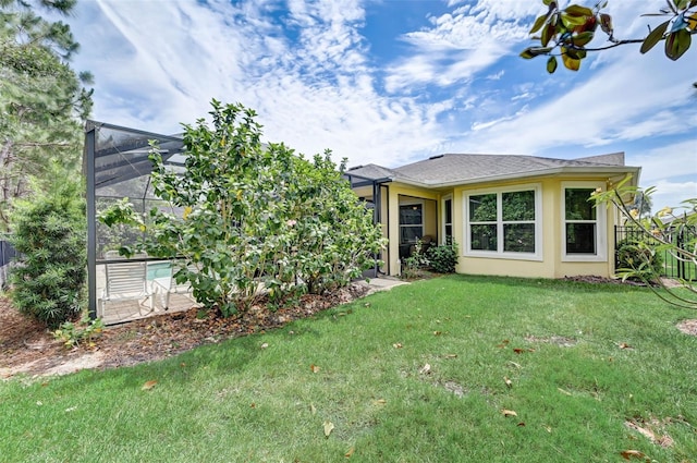 rear view of property with a lanai and a yard