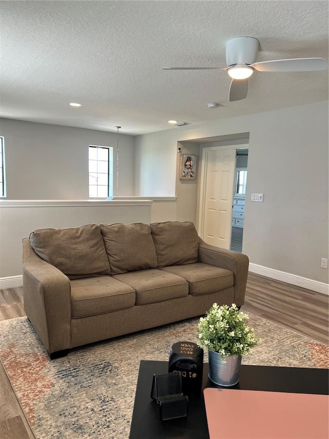 living room with hardwood / wood-style floors, ceiling fan, and a textured ceiling