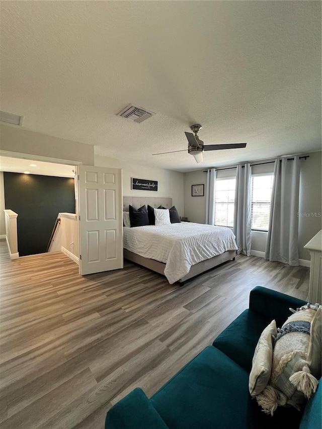 bedroom featuring ceiling fan, a textured ceiling, and wood-type flooring