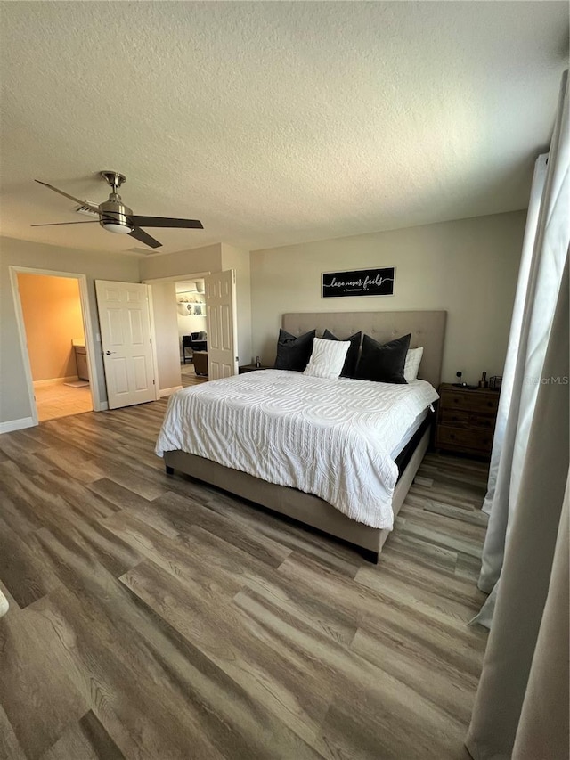 bedroom with a textured ceiling, ceiling fan, hardwood / wood-style floors, and ensuite bathroom