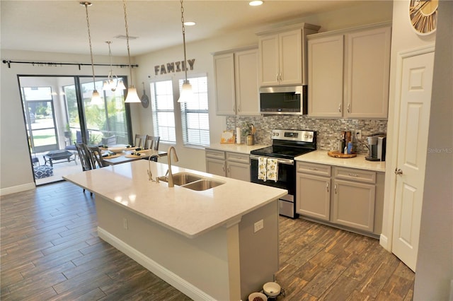 kitchen featuring hanging light fixtures, dark hardwood / wood-style flooring, appliances with stainless steel finishes, an island with sink, and sink