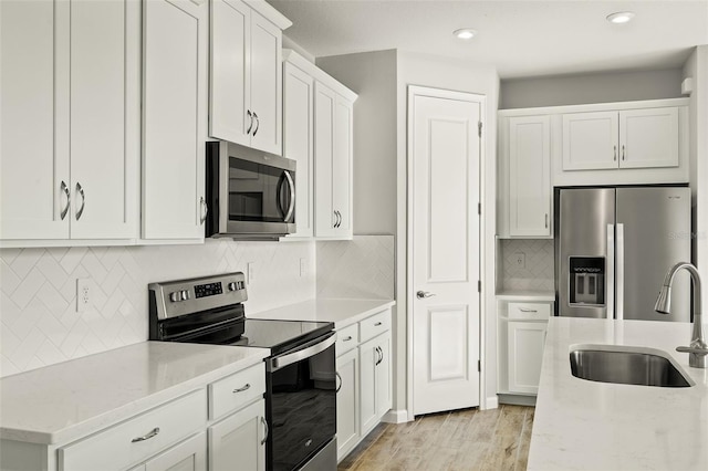 kitchen featuring white cabinets, sink, stainless steel appliances, and light hardwood / wood-style flooring