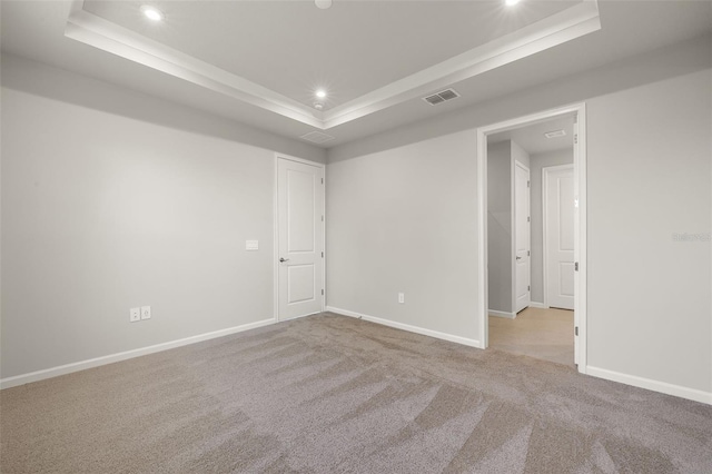 carpeted empty room featuring a raised ceiling