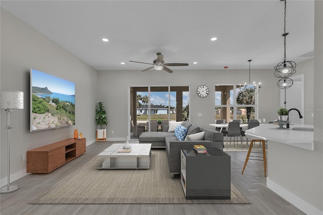 living room with ceiling fan with notable chandelier and sink