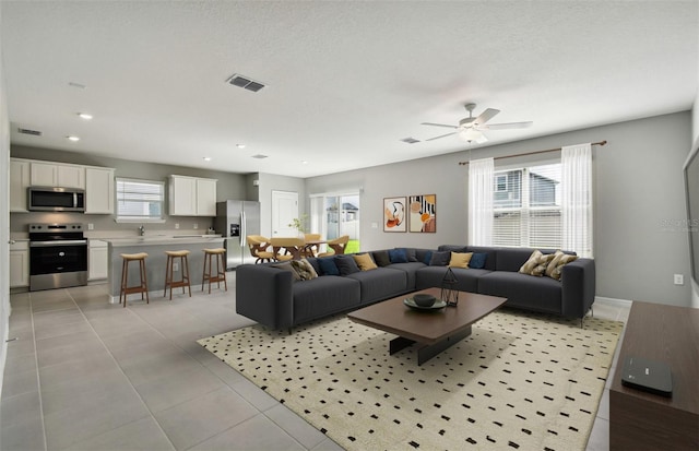 tiled living room with ceiling fan and sink