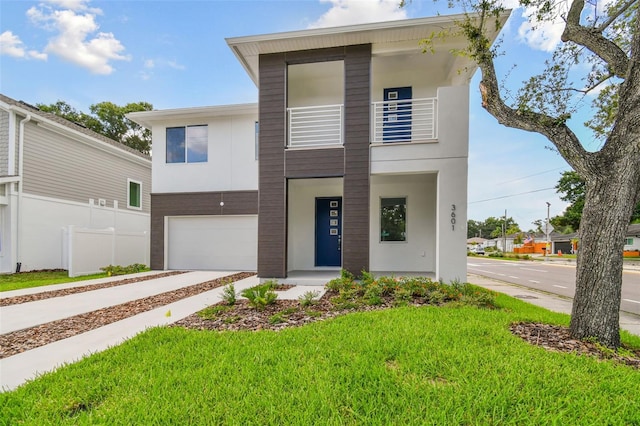 contemporary home featuring driveway, a balcony, an attached garage, fence, and a front yard