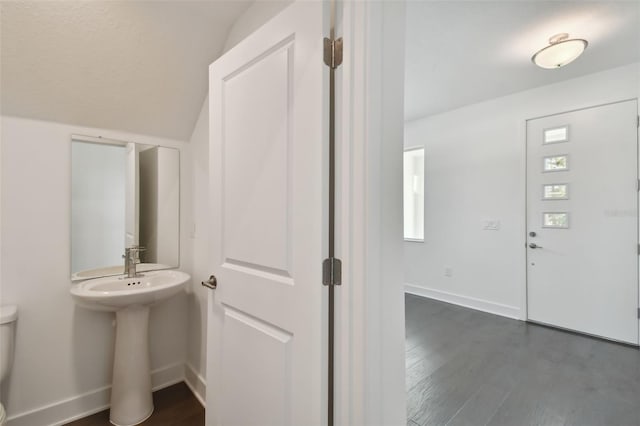 bathroom with hardwood / wood-style flooring, toilet, and vaulted ceiling