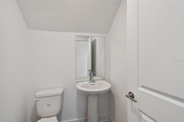 bathroom featuring a textured ceiling, toilet, and lofted ceiling