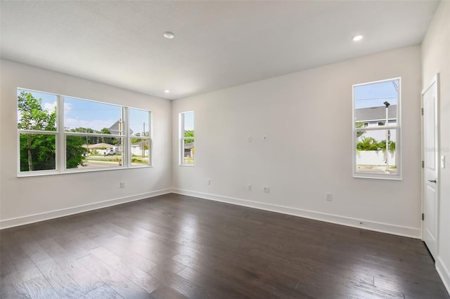 empty room featuring a healthy amount of sunlight and dark hardwood / wood-style floors