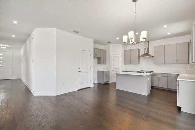 kitchen featuring gray cabinetry, a kitchen island, dark hardwood / wood-style flooring, and wall chimney range hood