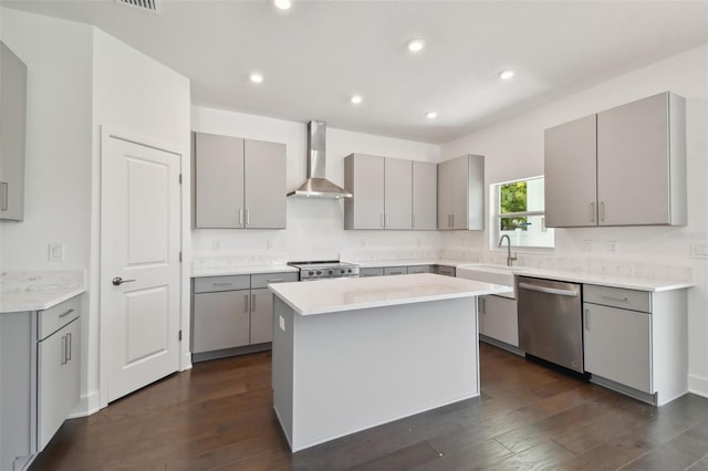 kitchen featuring stainless steel appliances, a kitchen island, wall chimney exhaust hood, and gray cabinetry