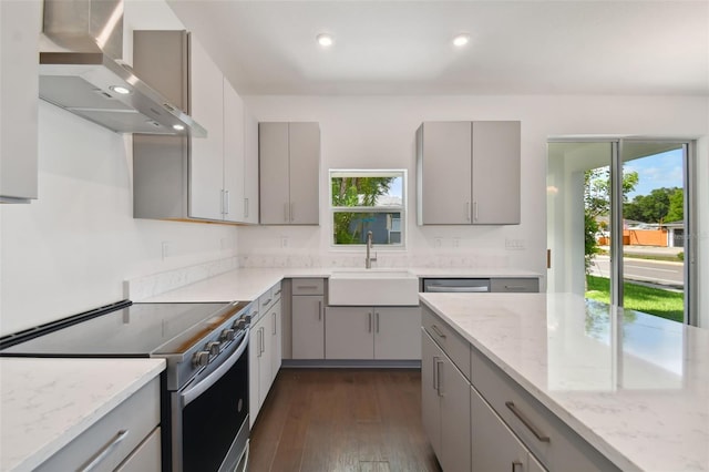 kitchen with stainless steel electric stove, gray cabinets, and wall chimney range hood