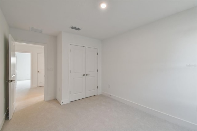 unfurnished bedroom featuring a closet and light colored carpet