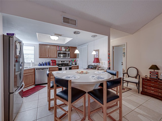 tiled dining room with a tray ceiling and a textured ceiling