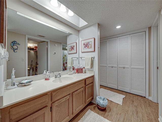 bathroom with vanity, a skylight, wood-type flooring, and a textured ceiling