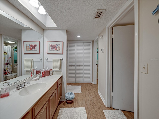 bathroom with vanity, toilet, hardwood / wood-style floors, and a textured ceiling