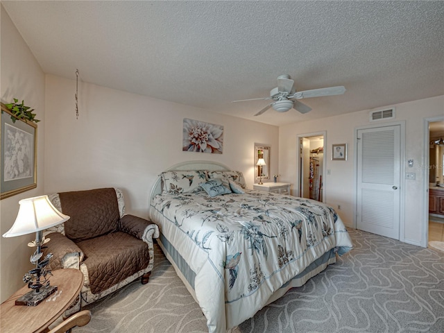 bedroom with ceiling fan, carpet, a textured ceiling, and ensuite bath