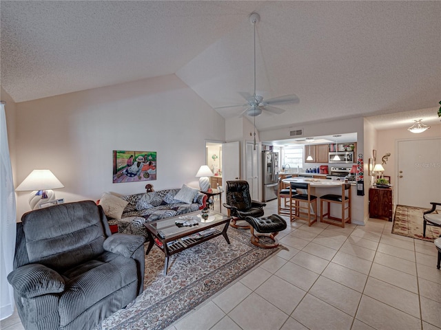 tiled living room featuring ceiling fan, lofted ceiling, and a textured ceiling