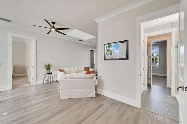 living room featuring ceiling fan, light hardwood / wood-style flooring, and a textured ceiling