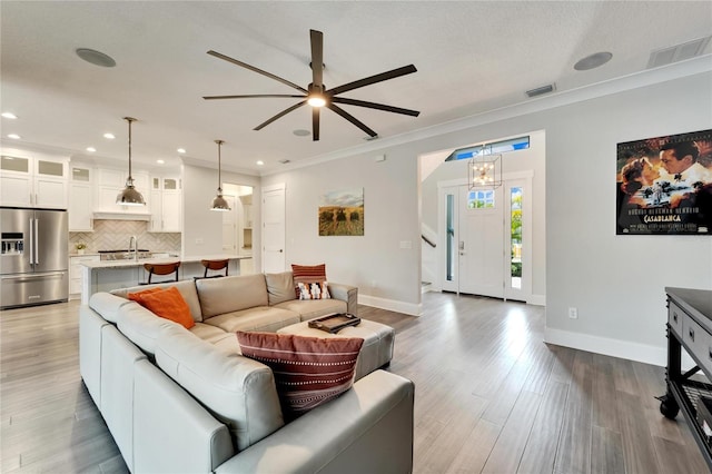 living room featuring ceiling fan, ornamental molding, and hardwood / wood-style floors