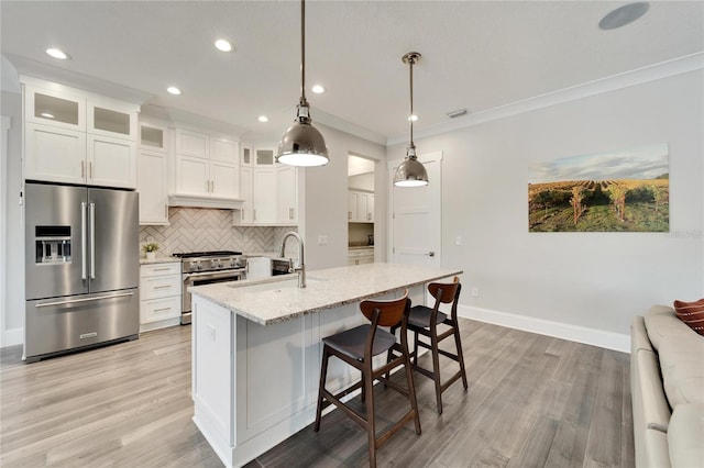 kitchen with tasteful backsplash, pendant lighting, wood-type flooring, sink, and appliances with stainless steel finishes