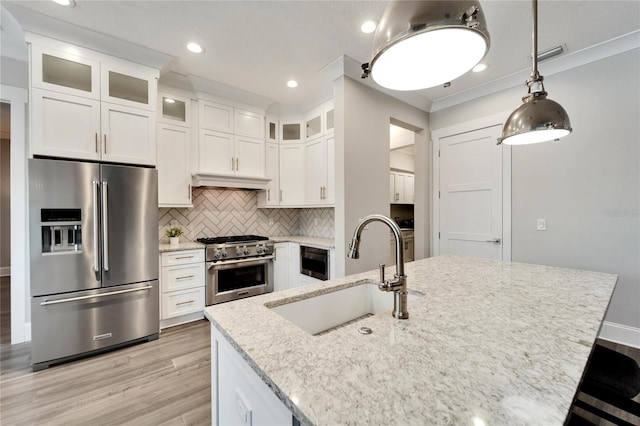 kitchen featuring white cabinets, backsplash, hanging light fixtures, appliances with stainless steel finishes, and sink