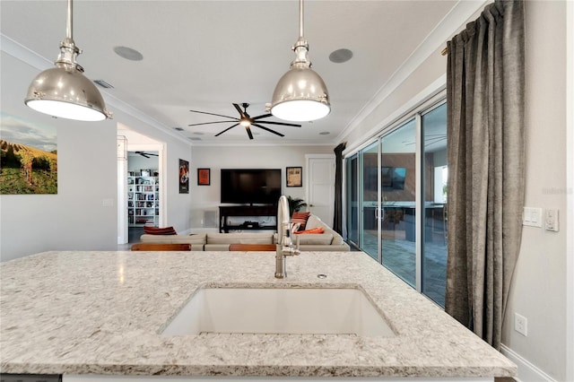 kitchen featuring decorative light fixtures, sink, ornamental molding, and light stone countertops