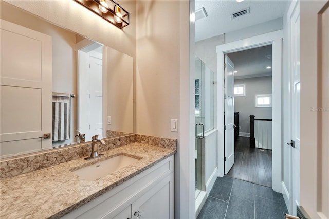 bathroom featuring vanity, a textured ceiling, tile floors, and a shower with door