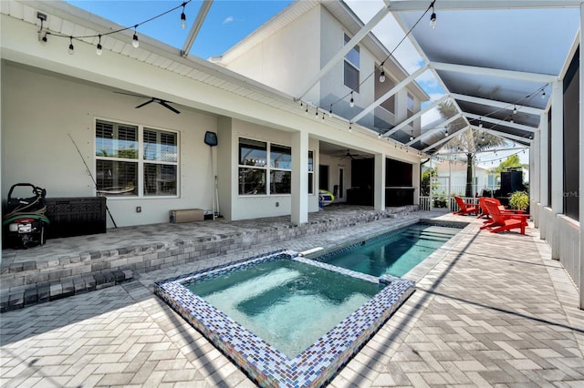 view of swimming pool with glass enclosure, an in ground hot tub, a patio area, and ceiling fan