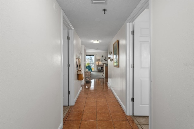 hall featuring tile floors and a textured ceiling