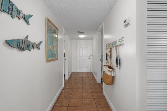 hall with dark tile flooring and a textured ceiling