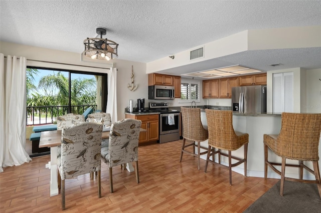 interior space with a textured ceiling, sink, and light hardwood / wood-style floors