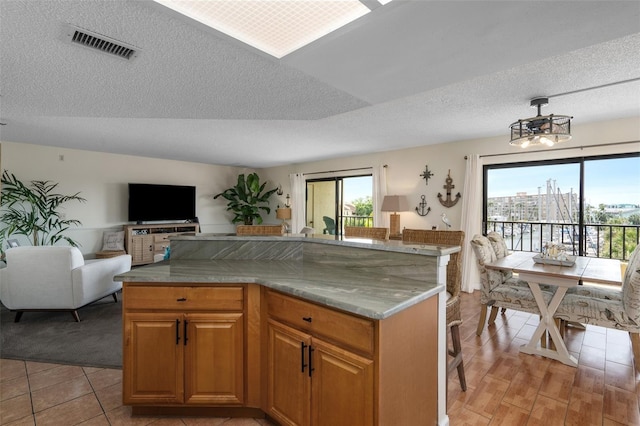 kitchen with a textured ceiling, a kitchen breakfast bar, light stone countertops, and light tile flooring