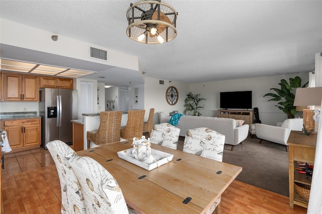 carpeted dining area with a textured ceiling