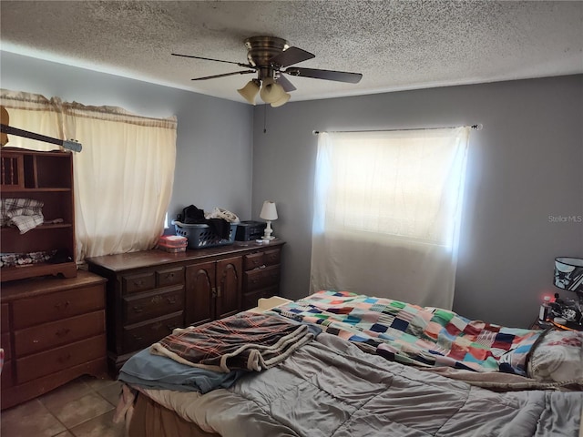 bedroom with a textured ceiling, ceiling fan, and tile floors