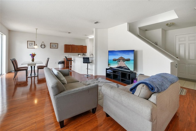 living room with a textured ceiling, light wood finished floors, and visible vents