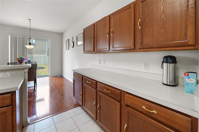 kitchen with a textured ceiling, light hardwood / wood-style flooring, and hanging light fixtures