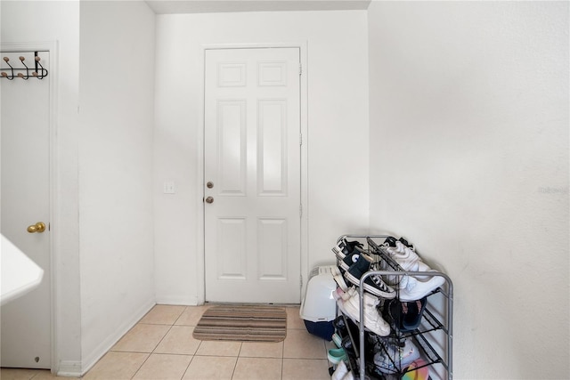 doorway featuring light tile patterned floors and baseboards