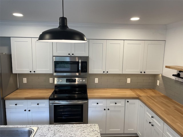 kitchen featuring wood counters, appliances with stainless steel finishes, and crown molding