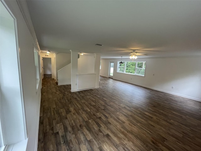 unfurnished living room with baseboards, dark wood-type flooring, visible vents, and a ceiling fan