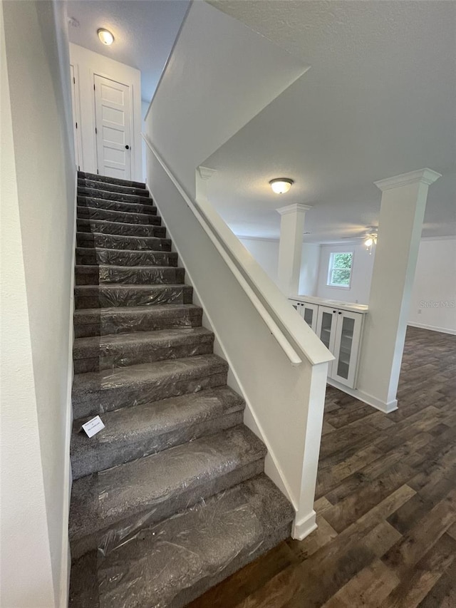 stairs featuring ornate columns, wood finished floors, and baseboards