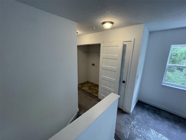 corridor featuring a textured ceiling and baseboards