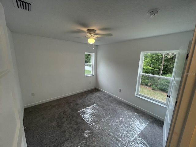 unfurnished room with carpet floors, visible vents, ceiling fan, and baseboards