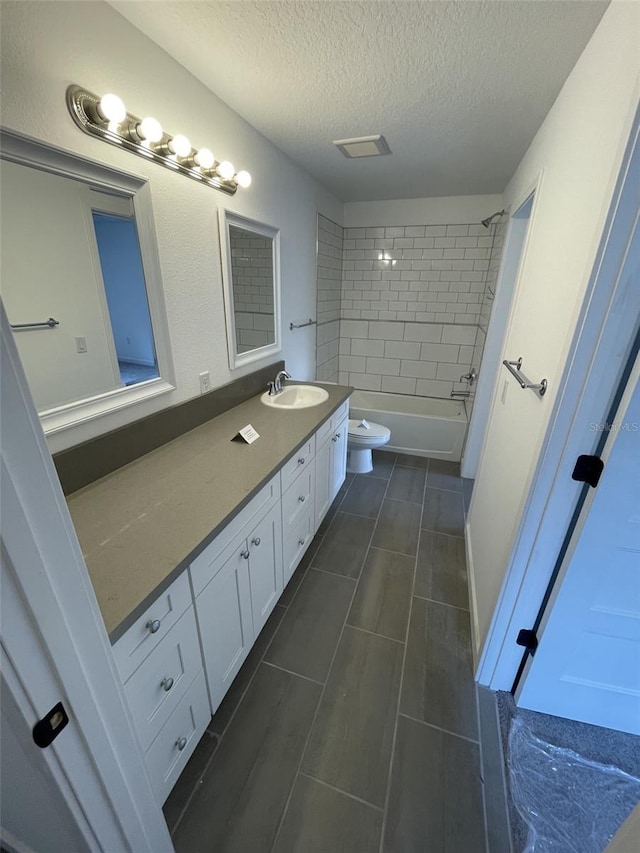 full bath with a textured ceiling, toilet, bathing tub / shower combination, and vanity