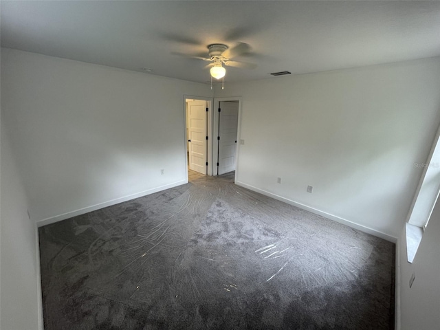 carpeted empty room featuring ceiling fan, visible vents, and baseboards